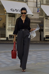 a lady wears a black silk blouse with a red handbag and sunglasses